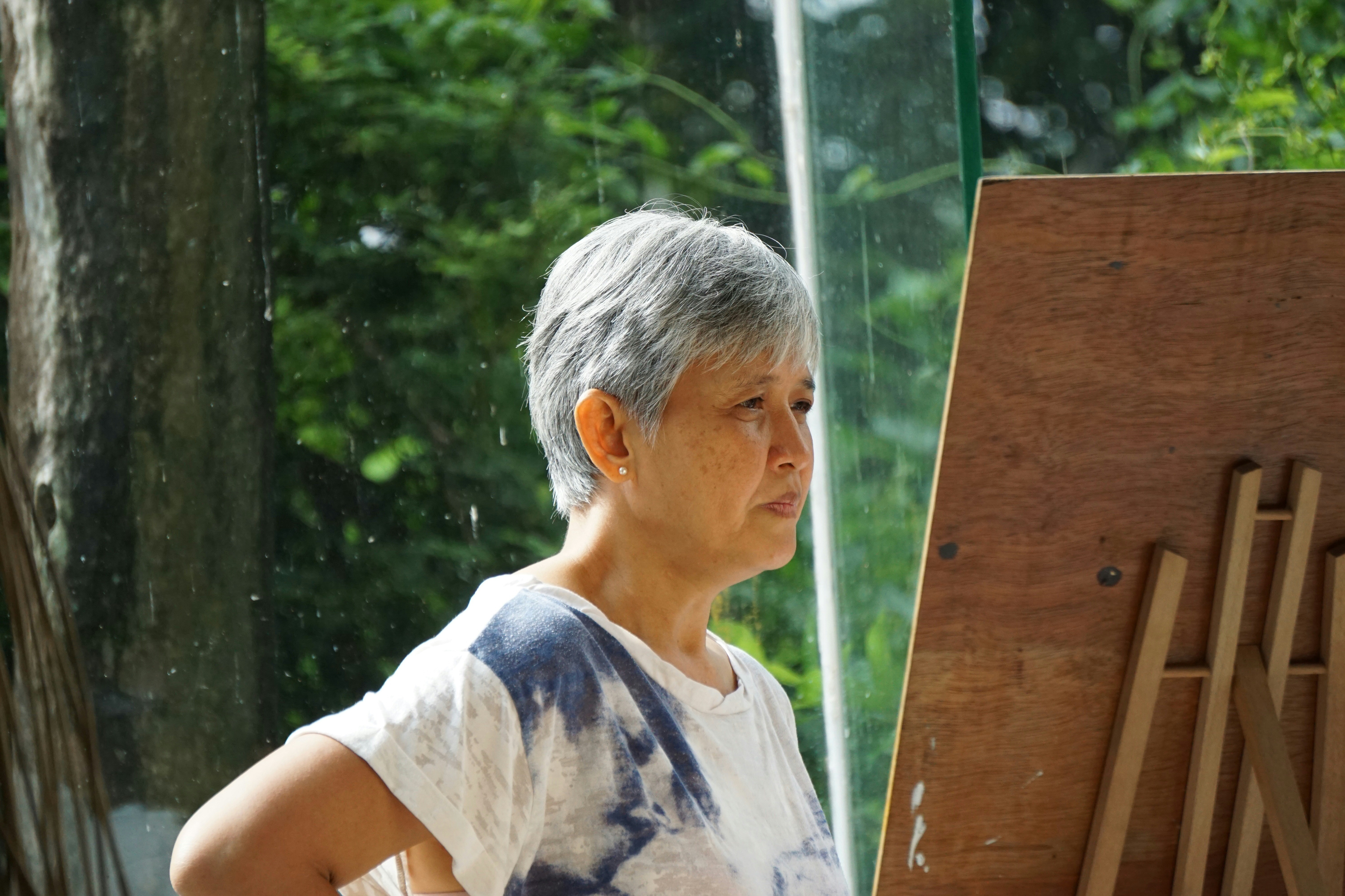 Older woman painting outdoors at an easel, focused and engaged in creative expression
